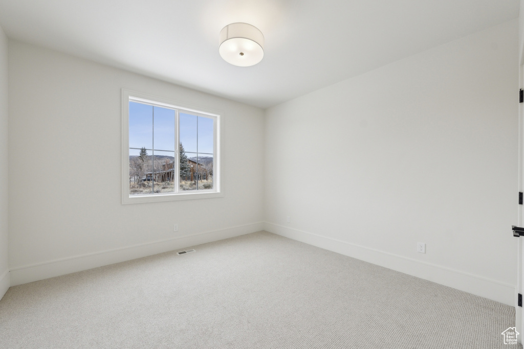 Unfurnished room with light colored carpet, visible vents, and baseboards
