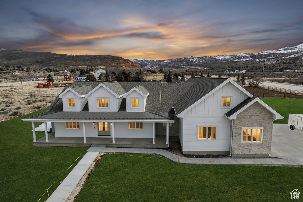 View of front of home featuring metal roof, a front yard, board and batten siding, a mountain view, and a porch