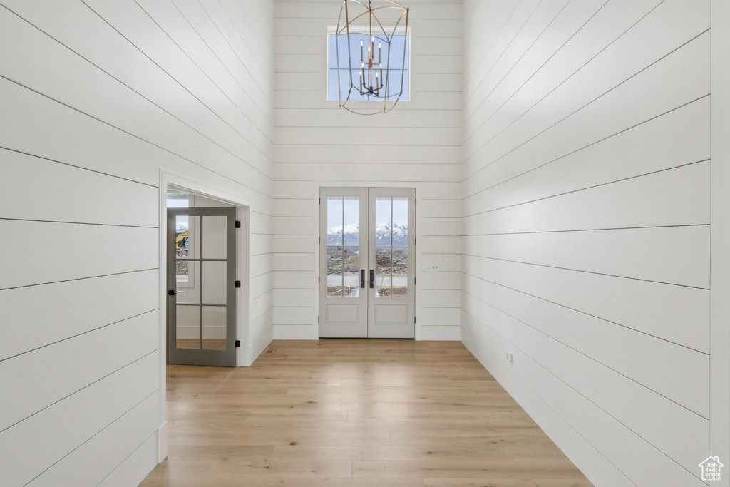Entrance foyer featuring a high ceiling, light wood-style flooring, french doors, and an inviting chandelier