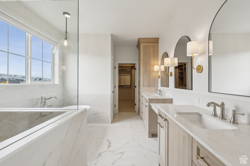 Full bathroom featuring marble finish floor, a walk in closet, vanity, and wainscoting