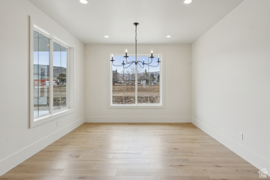 Unfurnished dining area featuring baseboards, recessed lighting, a notable chandelier, and light wood finished floors