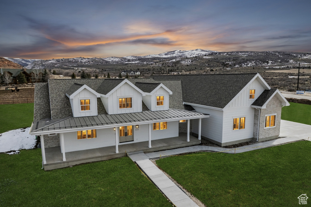 Modern inspired farmhouse featuring board and batten siding, a front yard, and a mountain view