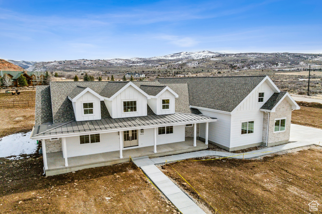 Modern inspired farmhouse with board and batten siding, a porch, a standing seam roof, and a mountain view