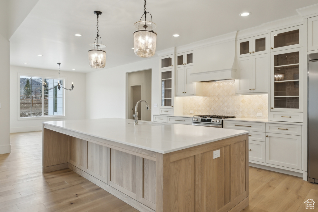 Kitchen featuring a sink, appliances with stainless steel finishes, a large island, custom range hood, and an inviting chandelier