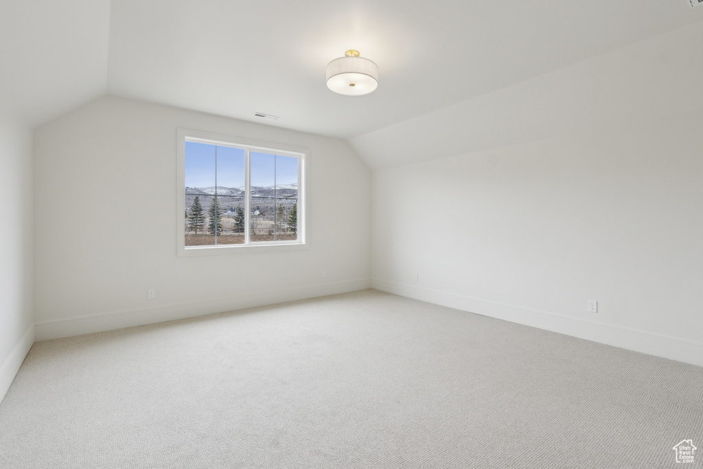 Bonus room featuring light colored carpet, vaulted ceiling, visible vents, and baseboards