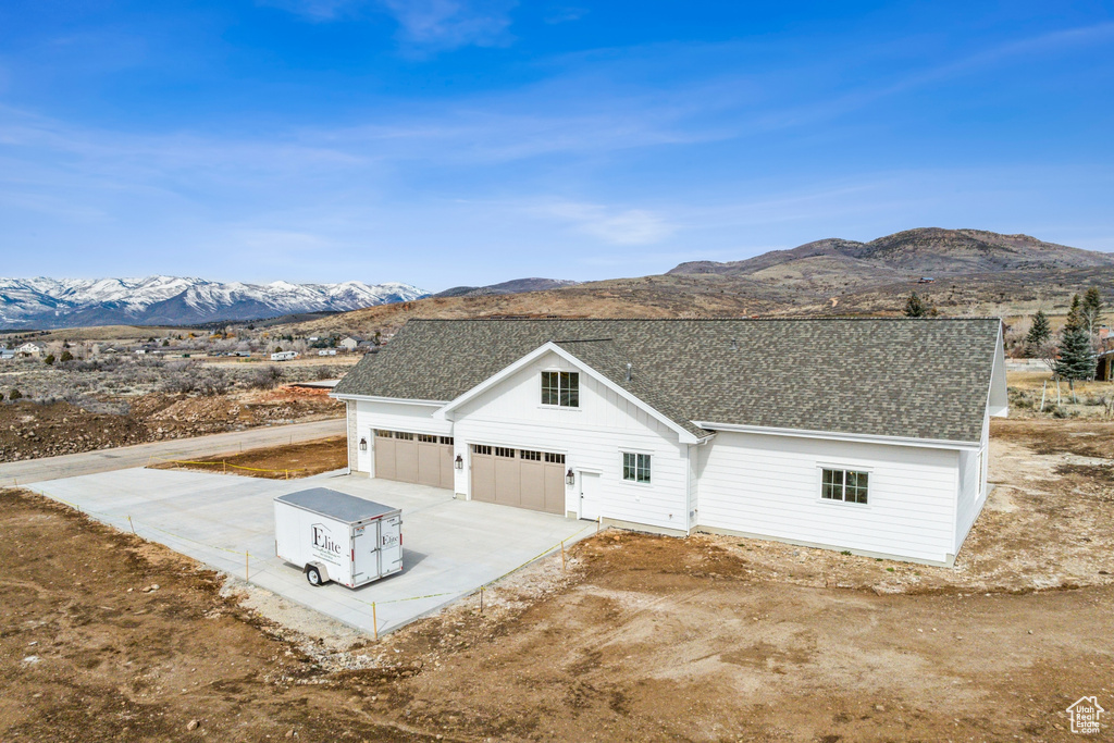 View of front of home with a garage, a mountain view, concrete driveway, and roof with shingles