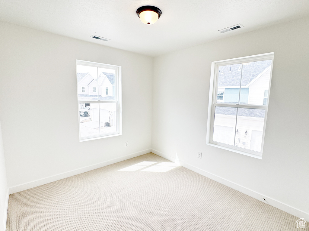 Empty room with baseboards, light colored carpet, and visible vents