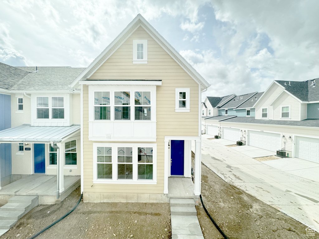 View of front of property featuring concrete driveway and central AC