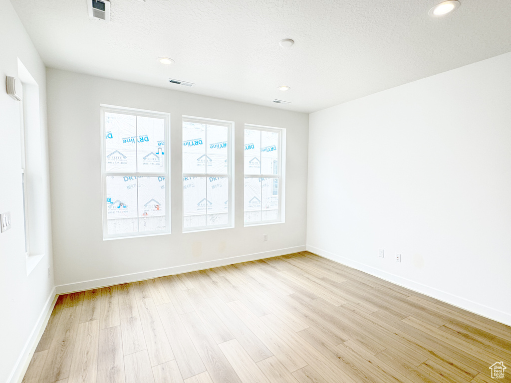 Spare room with light wood finished floors, baseboards, and visible vents