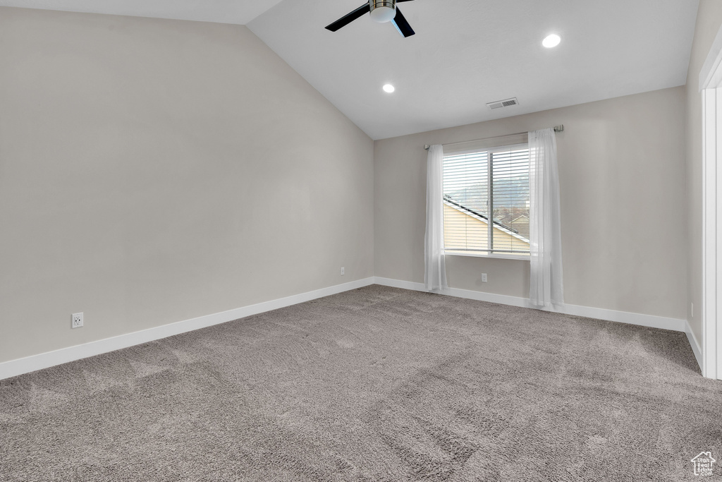 Spare room with carpet floors, vaulted ceiling, and ceiling fan