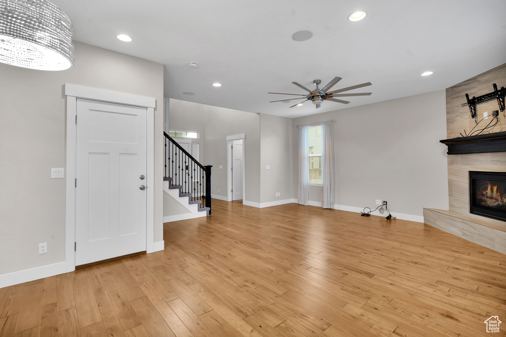 Unfurnished living room with ceiling fan, light hardwood / wood-style floors, and a high end fireplace