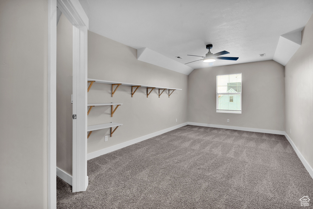 Carpeted empty room featuring ceiling fan and lofted ceiling