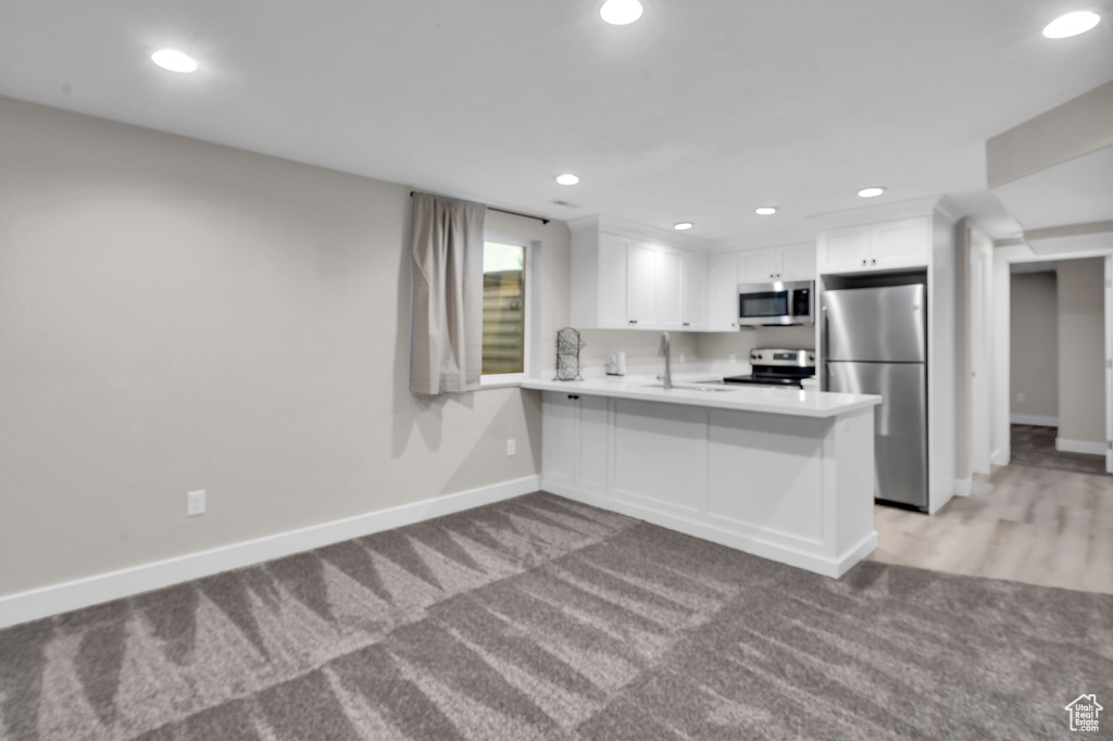 Kitchen with white cabinetry, sink, kitchen peninsula, a kitchen bar, and appliances with stainless steel finishes