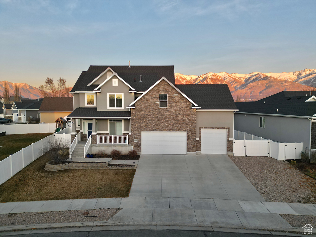 View of front of home featuring covered porch, a mountain view, and a garage