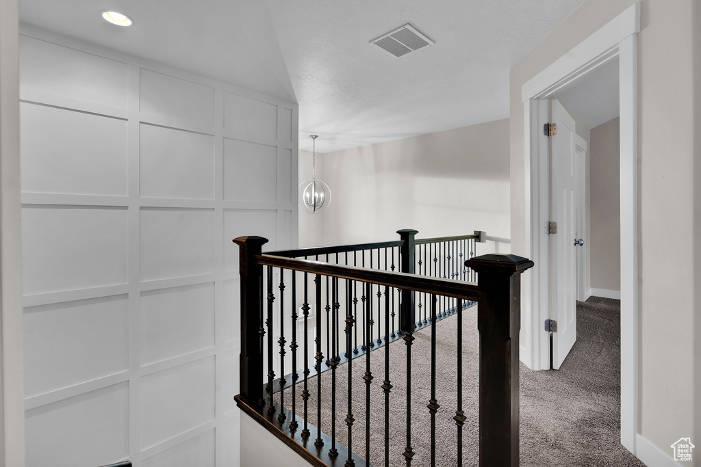 Staircase with a chandelier and carpet floors