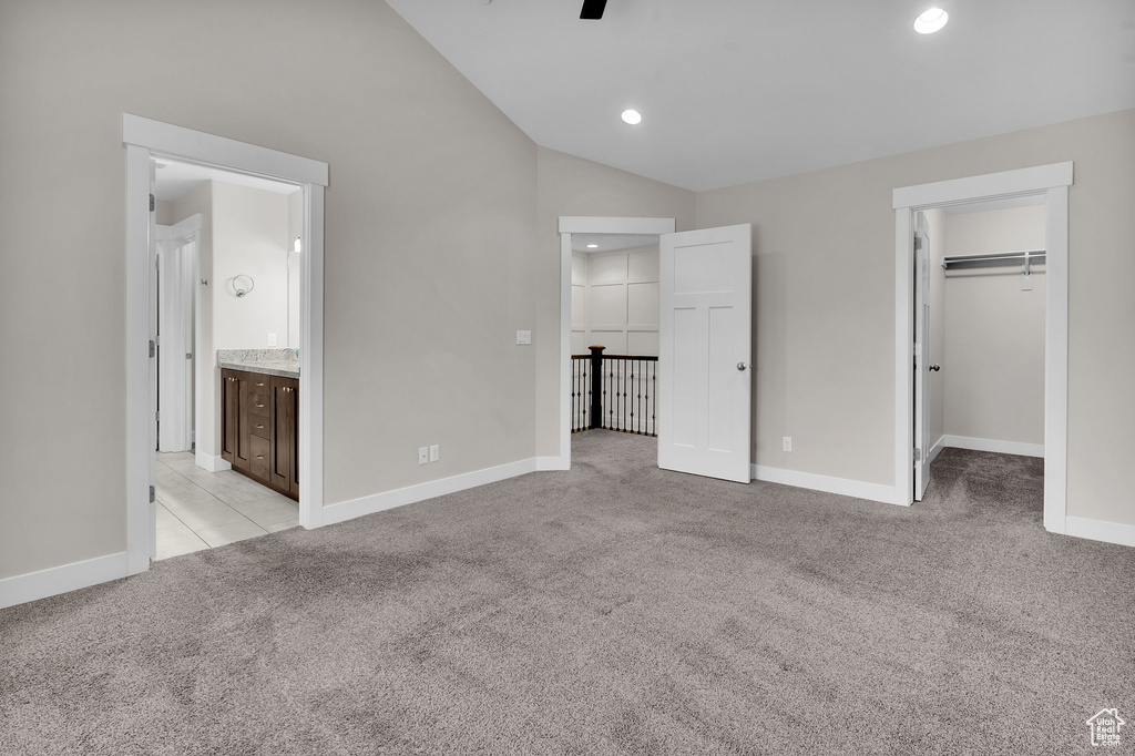 Unfurnished bedroom featuring connected bathroom, light colored carpet, a spacious closet, and a closet