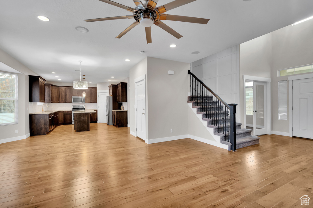Unfurnished living room featuring ceiling fan, sink, and light hardwood / wood-style floors
