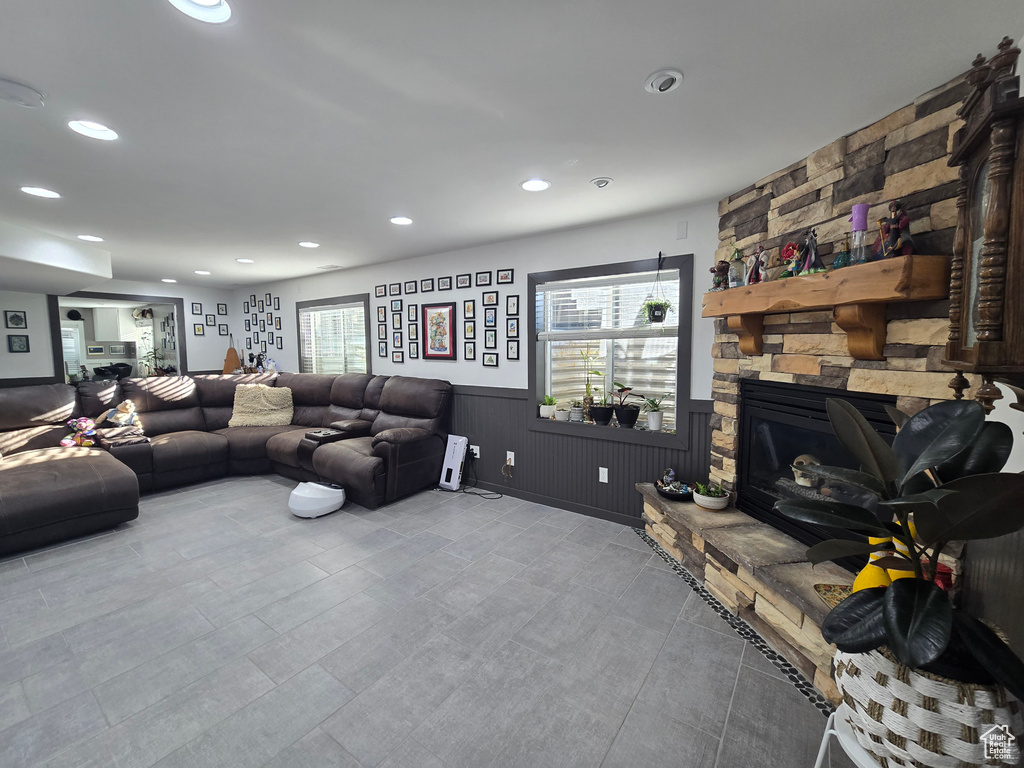 Living room with a wainscoted wall, a wealth of natural light, a stone fireplace, and recessed lighting