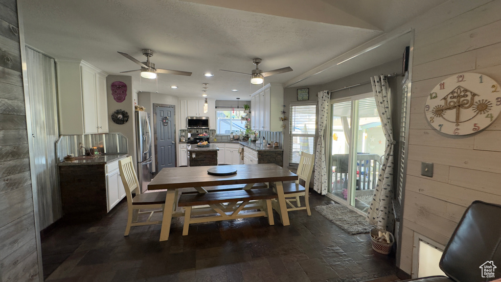 Dining room featuring wooden walls, plenty of natural light, ceiling fan, recessed lighting, and dark wood-style flooring