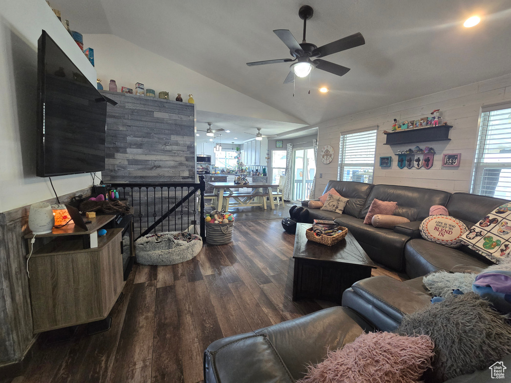 Living room with a ceiling fan, a wealth of natural light, vaulted ceiling, and wood finished floors