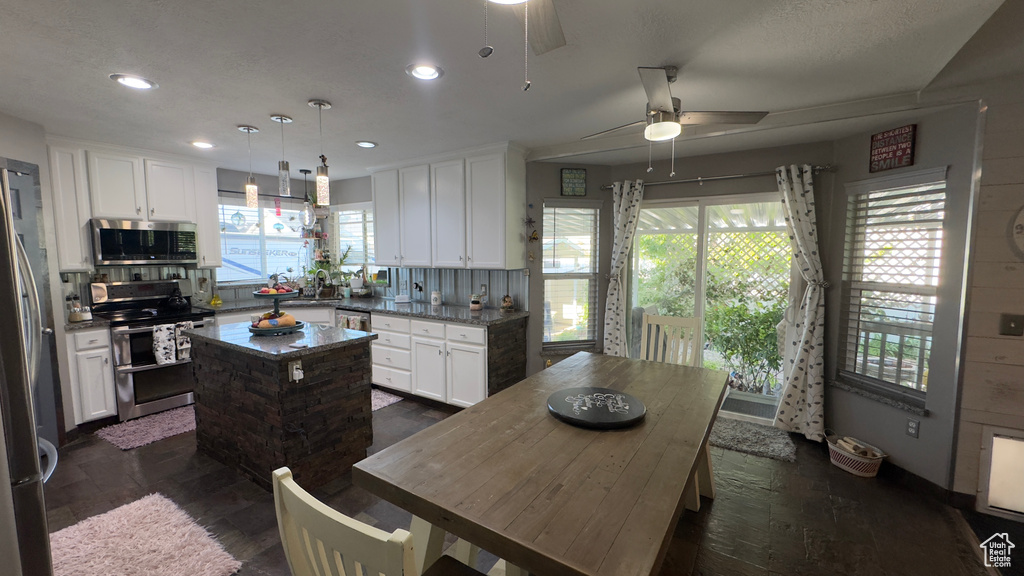 Kitchen featuring appliances with stainless steel finishes, a ceiling fan, a kitchen island, plenty of natural light, and recessed lighting