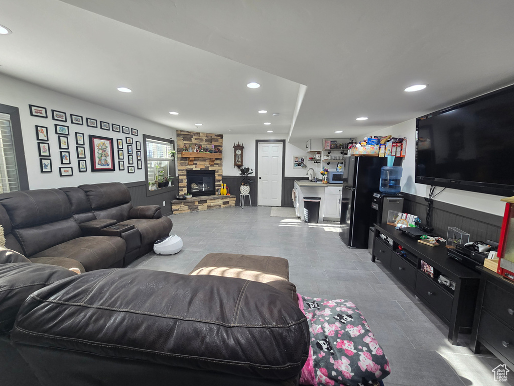Living room featuring recessed lighting, wainscoting, and a stone fireplace