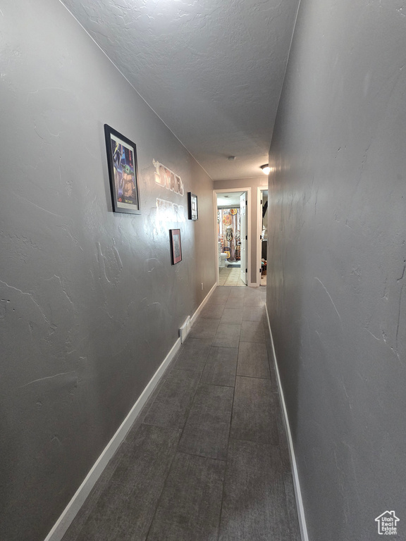 Hall featuring baseboards and a textured ceiling