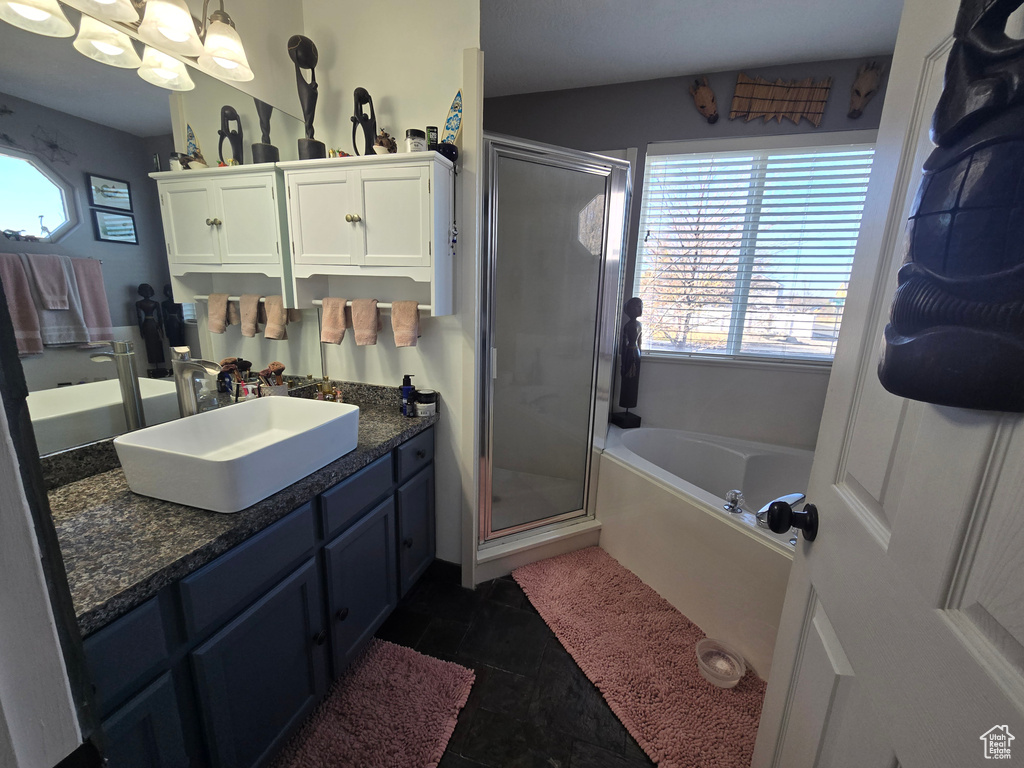 Full bath with tile patterned flooring, vanity, a stall shower, and a garden tub