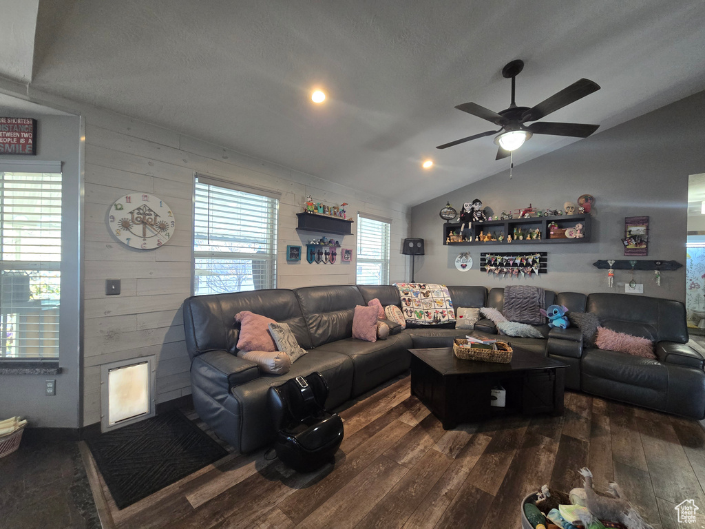 Living room featuring dark wood-style floors, vaulted ceiling, and ceiling fan