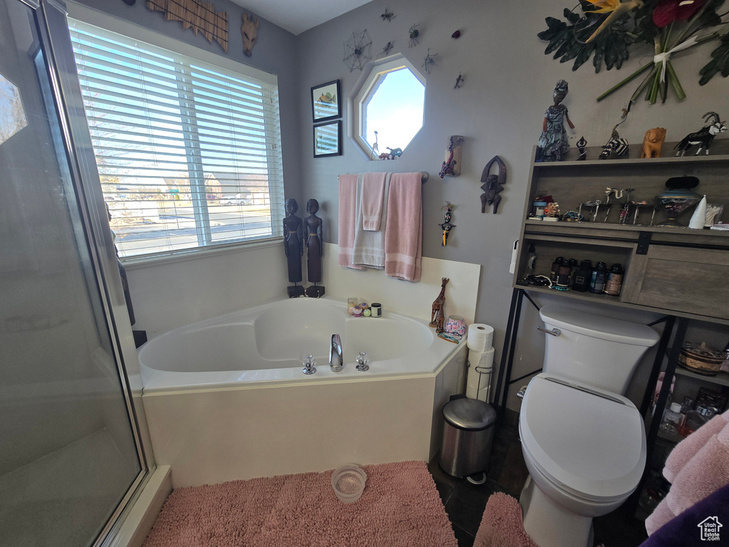 Bathroom featuring toilet, a garden tub, and a shower stall