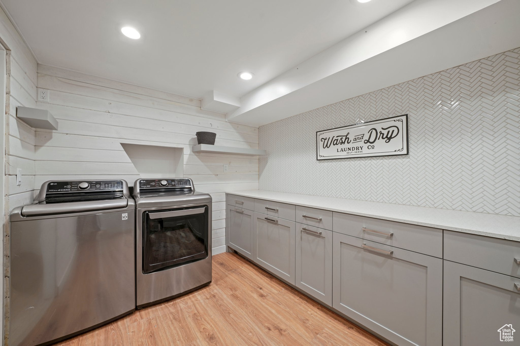 Clothes washing area with cabinet space, light wood-style flooring, recessed lighting, and separate washer and dryer