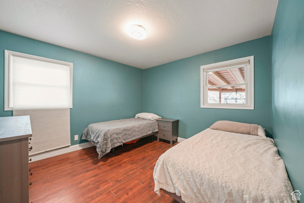 Bedroom with a textured ceiling, baseboards, and wood finished floors
