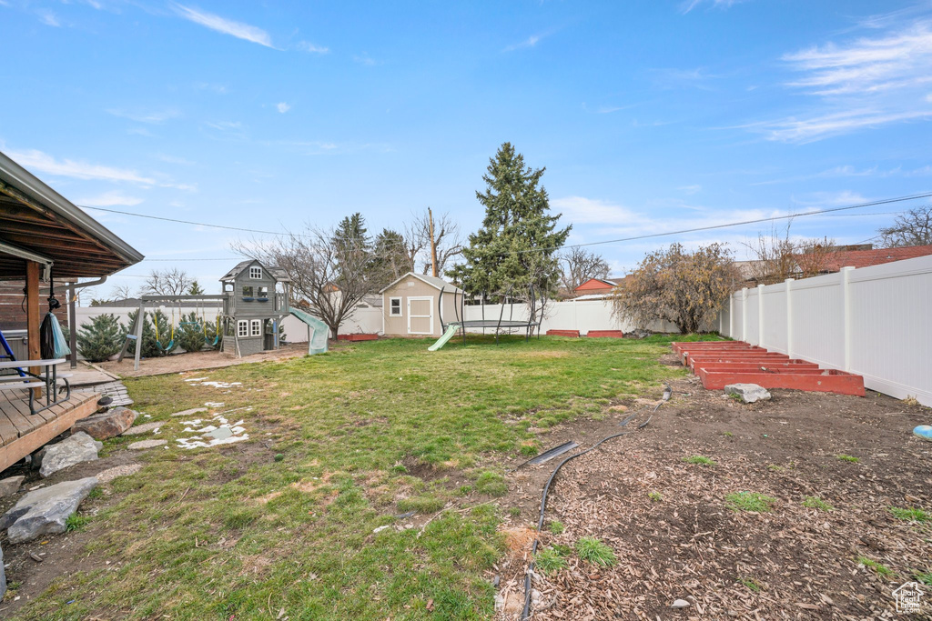 View of yard featuring a fenced backyard, a storage shed, an outdoor structure, and a playground