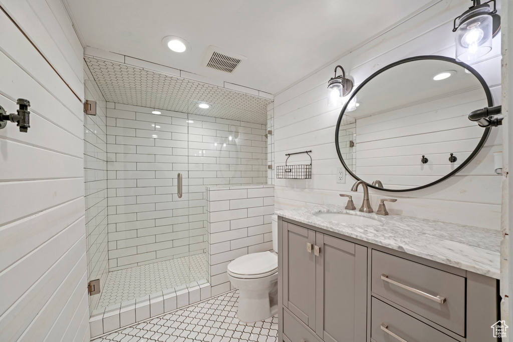 Bathroom featuring tile patterned flooring, visible vents, toilet, a stall shower, and vanity