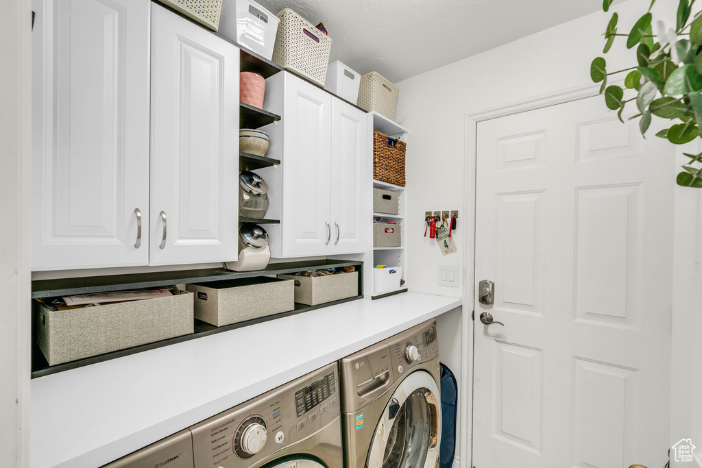 Washroom featuring cabinet space and independent washer and dryer