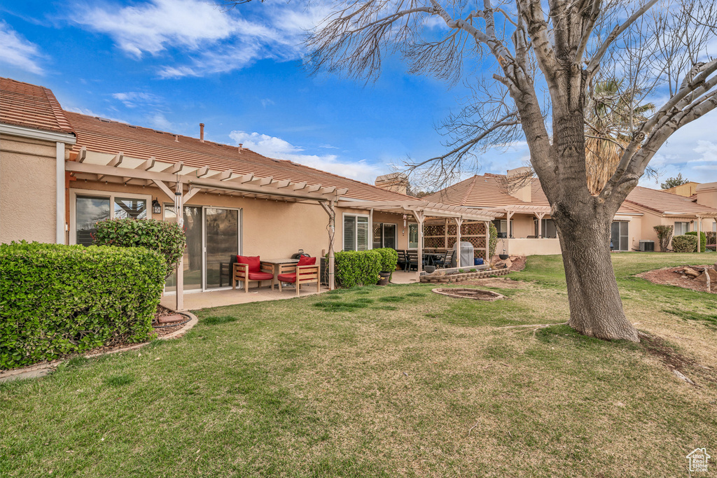 Back of property featuring a pergola, a patio, a yard, stucco siding, and a tiled roof