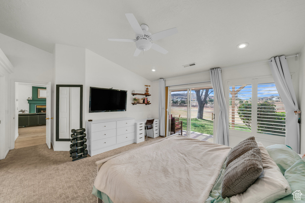 Bedroom with light colored carpet, vaulted ceiling, access to outside, visible vents, and a ceiling fan