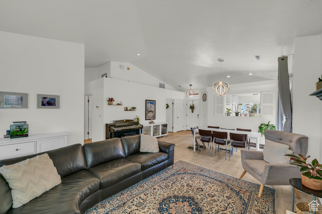 Living area with light wood finished floors, lofted ceiling, and visible vents