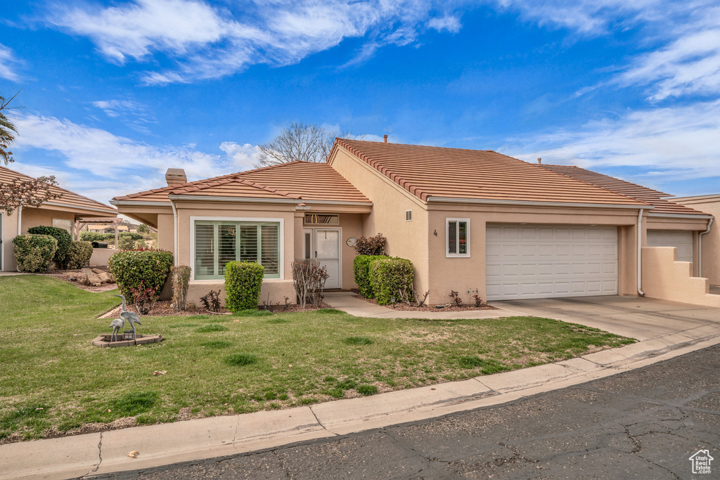 View of front of house with a garage, a tiled roof, stucco siding, and a chimney