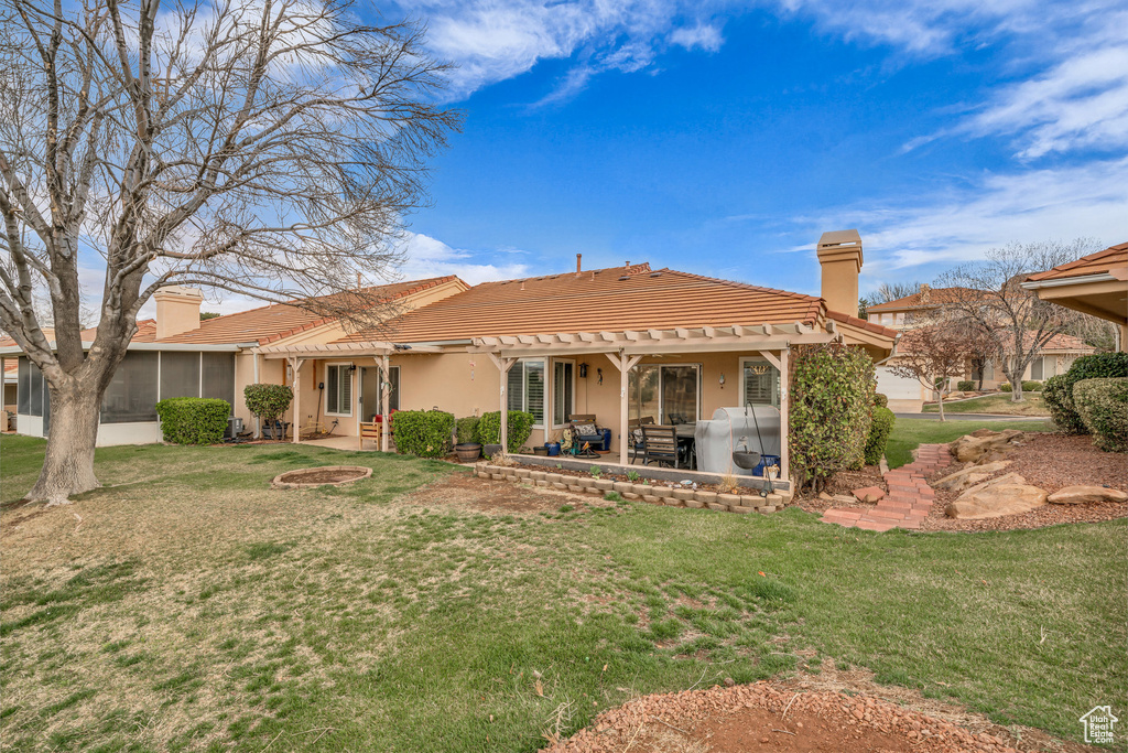 Rear view of property with a patio area, a chimney, a yard, and a tile roof