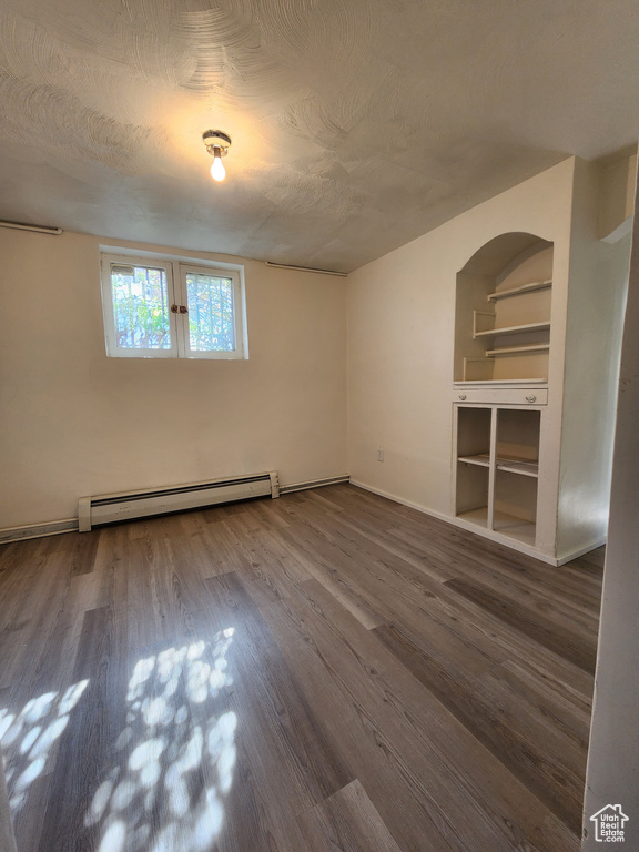 Spare room with a baseboard heating unit, wood finished floors, and baseboards