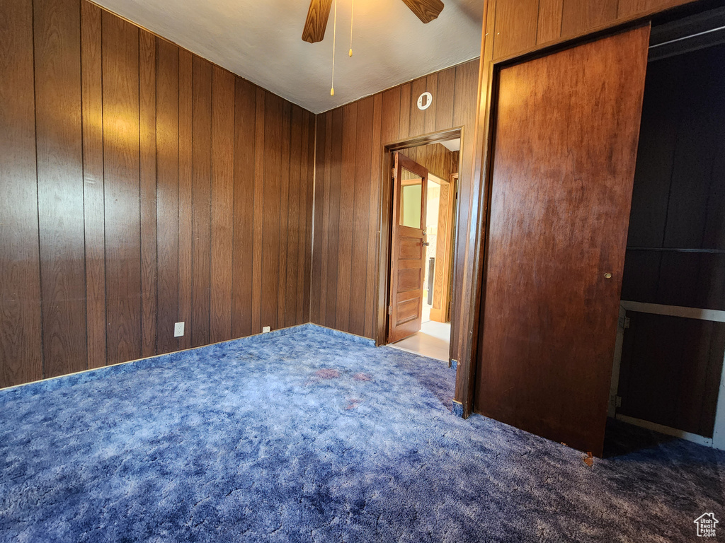 Unfurnished room with carpet, ceiling fan, and wooden walls