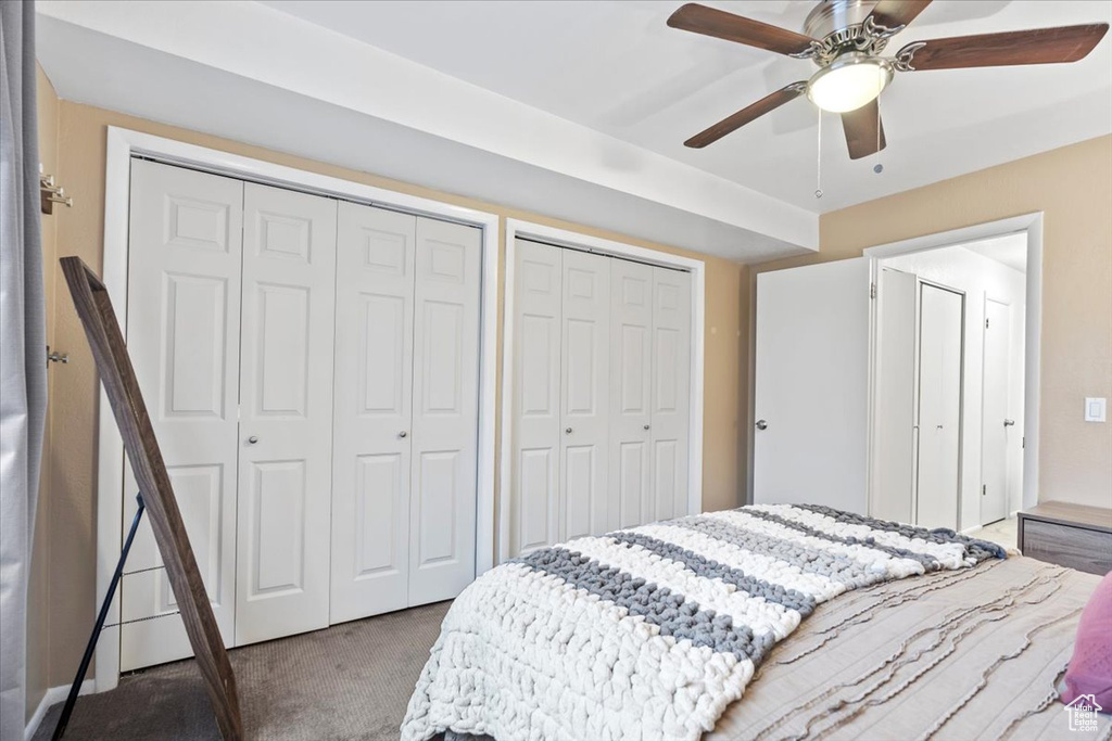 Carpeted bedroom featuring two closets and ceiling fan