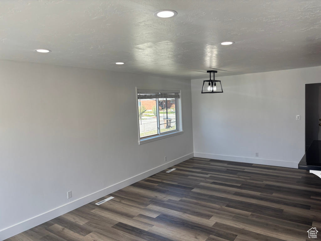 Unfurnished dining area featuring baseboards, a textured ceiling, dark wood-style floors, and recessed lighting