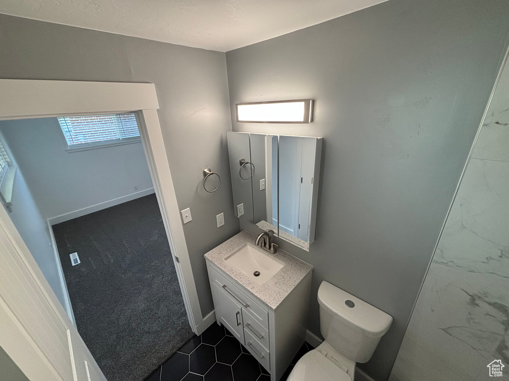 Bathroom with baseboards, toilet, and vanity