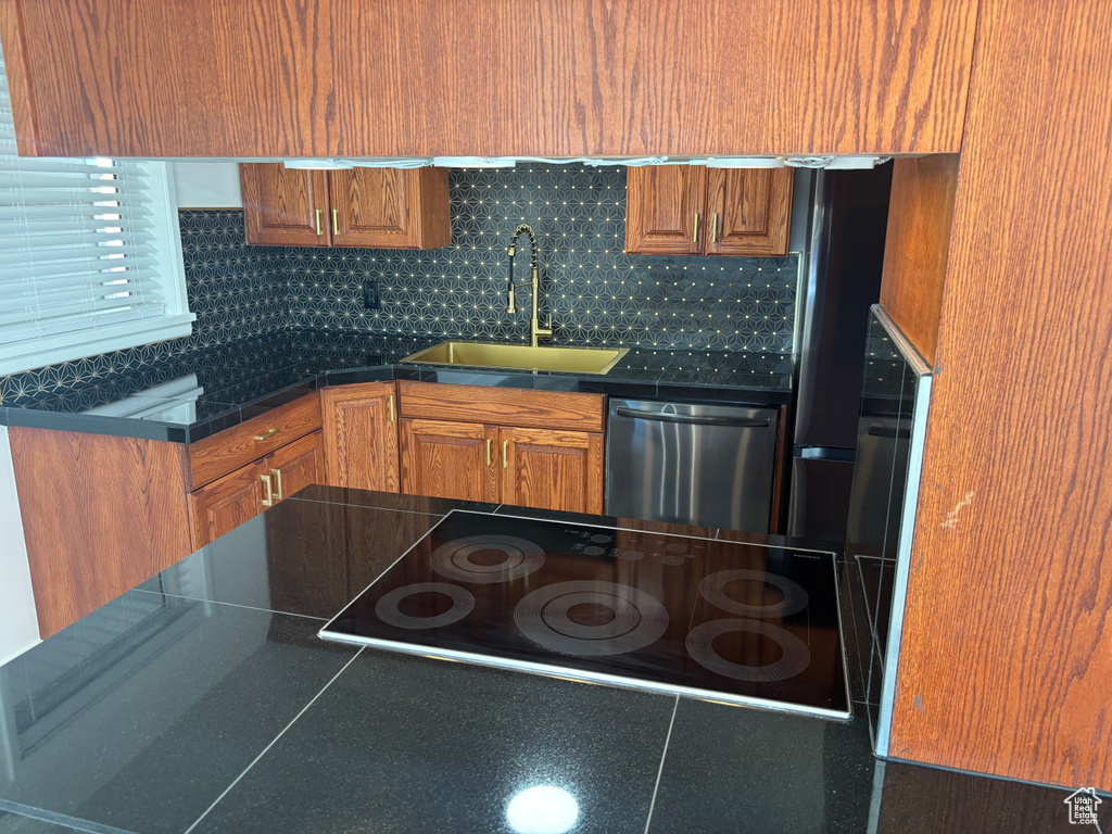 Kitchen with dishwasher, a sink, dark countertops, and brown cabinetry