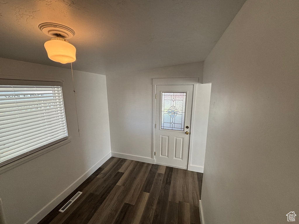 Doorway to outside with baseboards, dark wood-style flooring, lofted ceiling, and visible vents