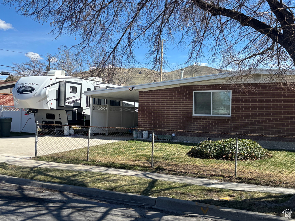 Exterior space featuring brick siding, an attached carport, driveway, and a fenced front yard