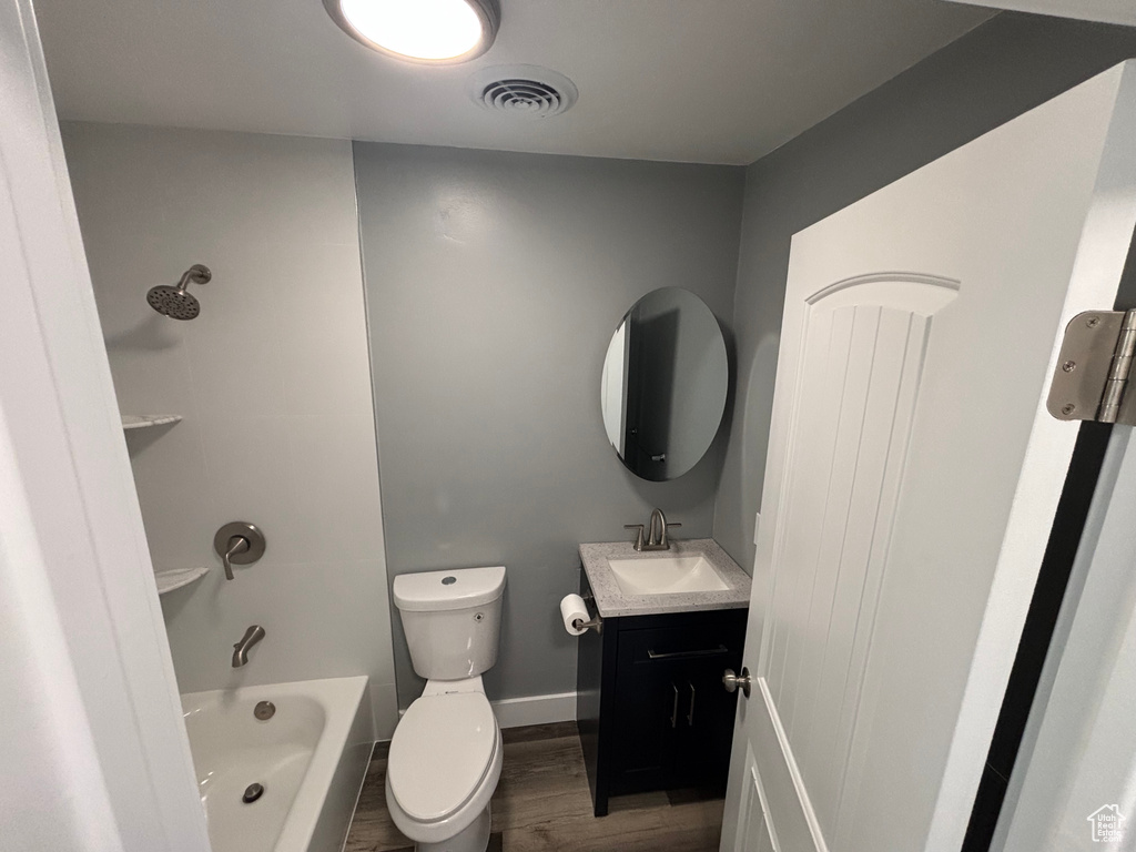 Bathroom with visible vents, toilet, wood finished floors, vanity, and shower / tub combination
