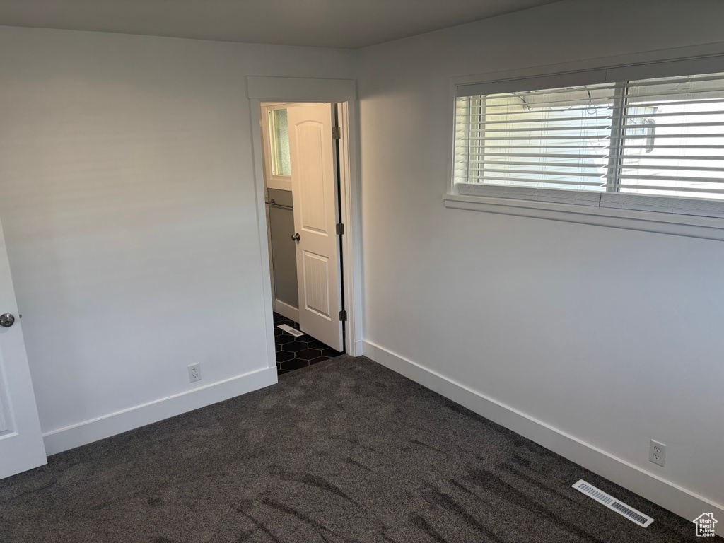 Empty room with baseboards, visible vents, and dark carpet